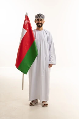 رجل عماني يقف مع علم سلطنة عمان الوطني