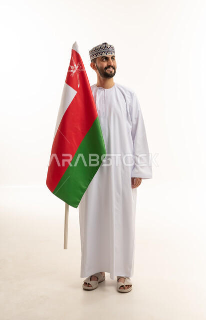 رجل عماني يحمل علم سلطنة عمان في الاستوديو