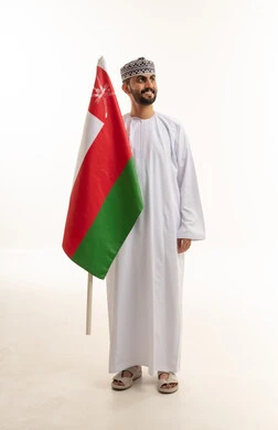 رجل عماني يحمل علم سلطنة عمان في الاستوديو