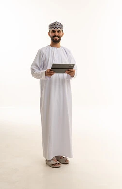 رجل عُماني بالزي التقليدي يحمل جهازاً لوحياً