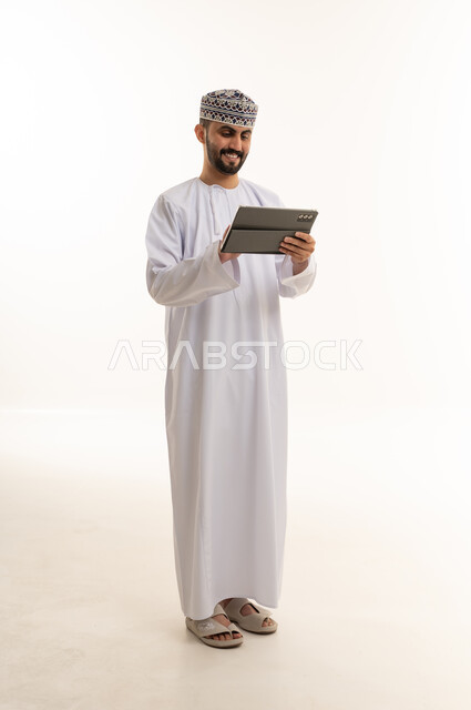 Omani Man in Traditional Dress Using Tablet on White Background