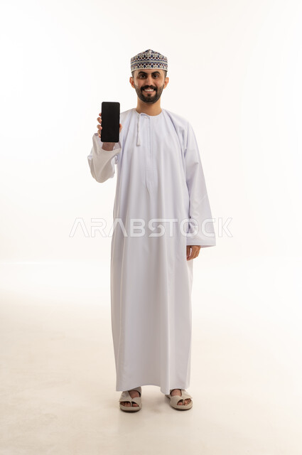 رجل عماني بالزي التقليدي يمسك هاتف ذكي