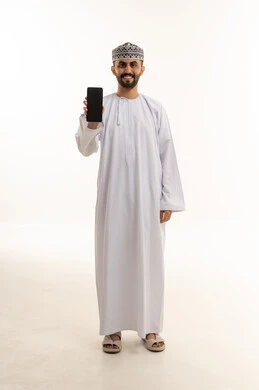رجل عماني بالزي التقليدي يمسك هاتف ذكي
