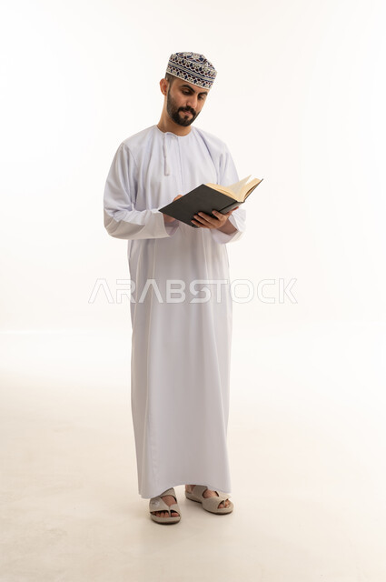 Omani Man in Traditional Dishdasha Reading a Book