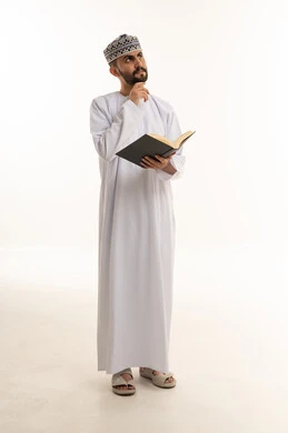 رجل عماني بالزي التقليدي يقرأ كتاب ويفكر