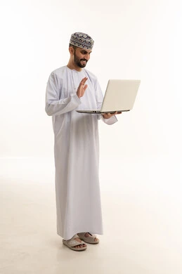 رجل عُماني بالزي التقليدي يستخدم الحاسوب المحمول