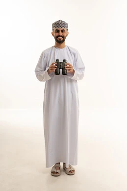 رجل عُماني يحمل منظاراً مكبراً بالزي التقليدي