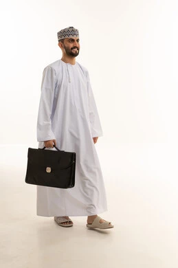 رجل أعمال عماني يمشي بحقيبة عمل على خلفية بيضاء