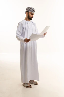 رجل عماني بالزي التقليدي يقرأ وثائق ورقية