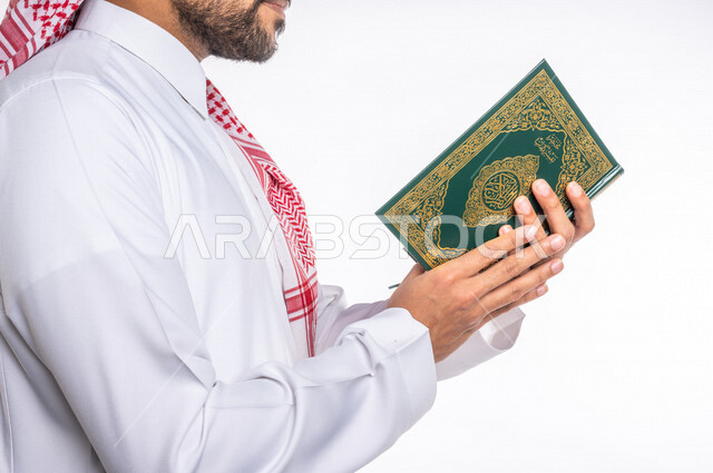 تصوير مقرب لرجل عربي سعودي خليجي يرتدي الثوب الأبيض السعودي يحمل القرآن الكريم, قراءة القرآن, الشعور بالخشوع والطمأنينه, الإكثار من ذكر الله تعالى, الإجتهاد في العباده, التقرب الى الله في شهر رمضان المبارك, إسلاميات وعبادات, جمعه مباركه