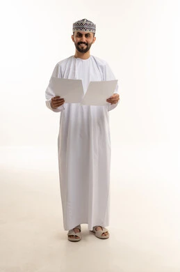 رجل عُماني بالزي التقليدي يمسك أوراقاً رسمية