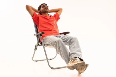 رجل سعودي مسترخي على كرسي تخييم خلفية بيضاء