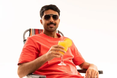 رجل سعودي مع عصير برتقال على كرسي شاطئ