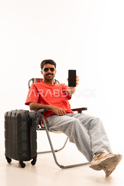 رجل مع حقيبة سفر يحمل هاتفاً ذكياً