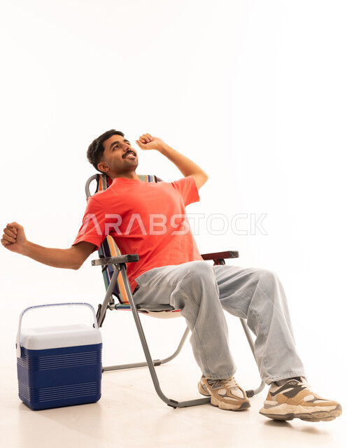رجل سعودي يتمدد على كرسي تخييم خلفية بيضاء