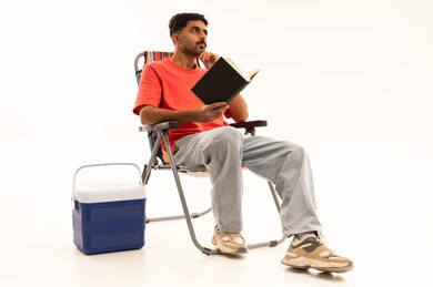 رجل سعودي يجلس على كرسي تخييم يقرأ كتاباً