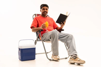 رجل عربي يسترخي على كرسي تخييم مع كتاب