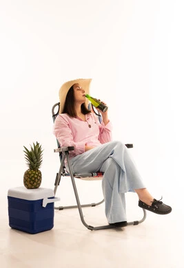 امرأة تسترخي على كرسي التخييم مع مشروب