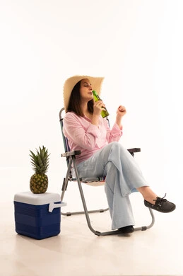 امرأة عربية تسترخي على كرسي مع صندوق تبريد وأناناس