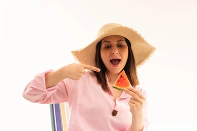 امرأة ترتدي قبعة شمس وتحمل شريحة بطيخ