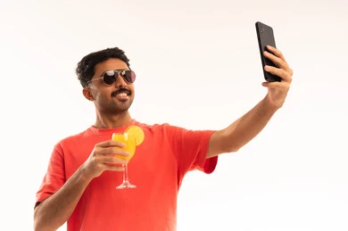 شاب يلتقط سيلفي مع عصير برتقال بخلفية بيضاء
