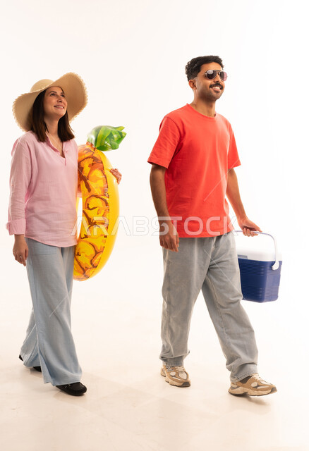 زوجان عربيان يحملان معدات الشاطئ في الاستوديو