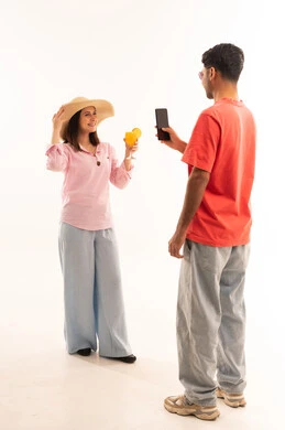 شاب يصور امرأة تحمل كوب عصير في استوديو