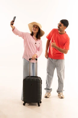 زوجان عربيان مع حقيبة سفر يلتقطان سيلفي