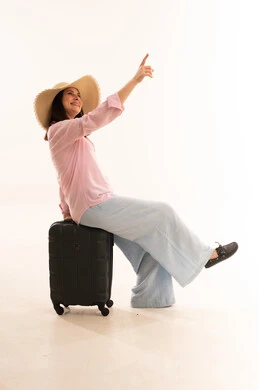 امرأة مسافرة تجلس على حقيبة سفر خلفية بيضاء