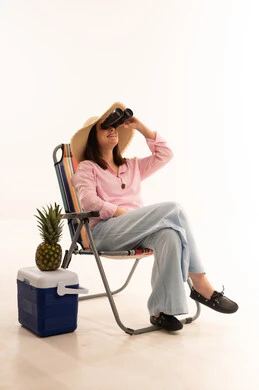 امرأة على كرسي الشاطئ تستخدم المنظار في الاستوديو