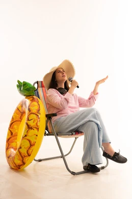 امرأة تغني على كرسي الشاطئ مع عوامة أناناس