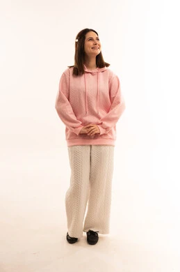 امرأة مبتسمة ترتدي سترة وردية بخلفية بيضاء