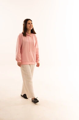 امرأة مبتسمة تمشي في الاستوديو بسترة وردية