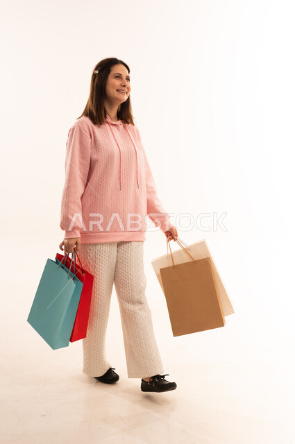 امرأة مبتسمة تمشي مع حقائب تسوق ملونة