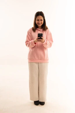 امرأة عربية تمسك هاتف ذكي بسترة وردية في الاستوديو