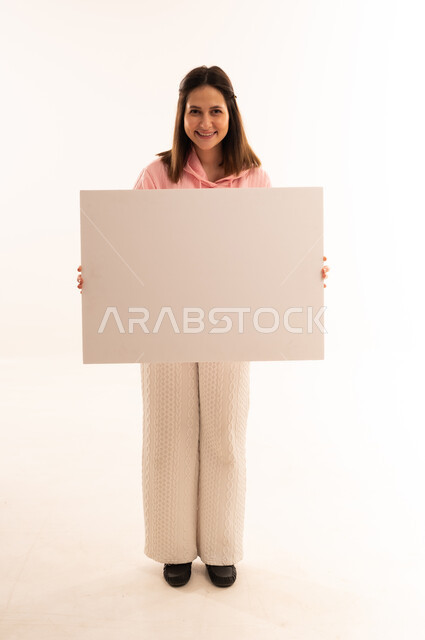 امرأة شابة تحمل لوحة فارغة في استوديو أبيض