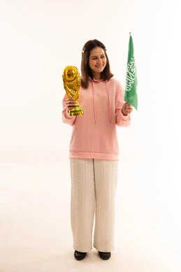 امرأة سعودية تحمل كأس ذهبي وعلم السعودية