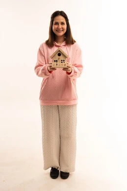 امرأة عربية تحمل نموذج منزل على خلفية بيضاء