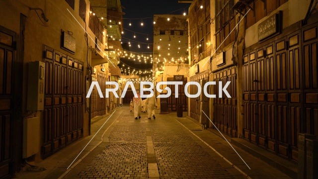 رجال سعوديون يسيرون في زقاق بجدة التاريخية ليلاً