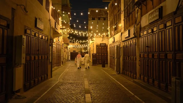 رجال سعوديون يسيرون في زقاق بجدة التاريخية ليلاً