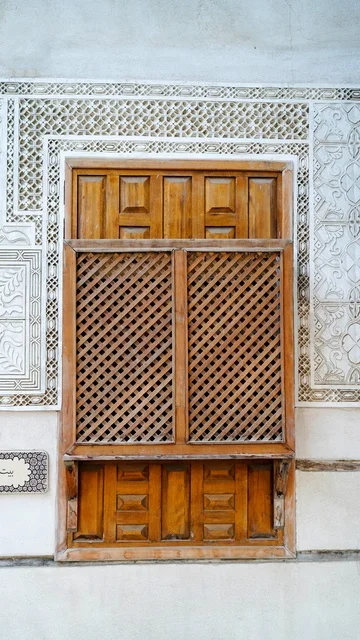 نافذة مشربية خشبية تقليدية على جدار مزخرف بالنقوش