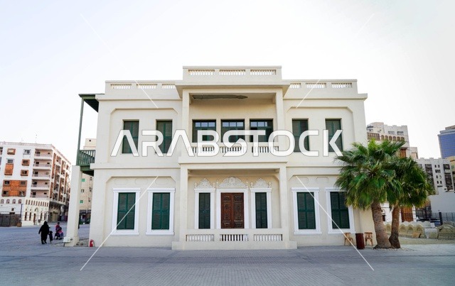 مبنى تراثي أبيض بنوافذ خضراء ونخيل