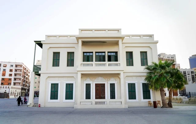 مبنى تراثي أبيض بنوافذ خضراء ونخيل