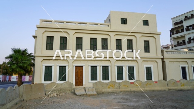 مبنى تقليدي قديم من طابقين مع نوافذ خضراء وحواجز خرسانية