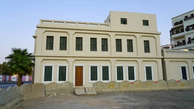 مبنى تقليدي قديم من طابقين مع نوافذ خضراء وحواجز خرسانية