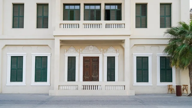 واجهة مبنى تقليدي مع نوافذ خضراء ومصاريع