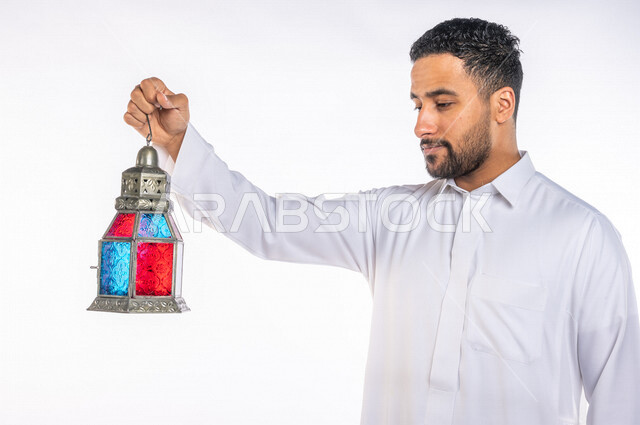 بورتريه لرجل عربي سعودي خليجي يرتدي الزي السعودي يحمل فانوس شهر  رمضان, زينه و أجواء رمضانيه, مناسبات دينيه, البهجه والسرور بقدوم رمضان, الإستعداد لشهر رمضان المبارك, تحف وديكورات