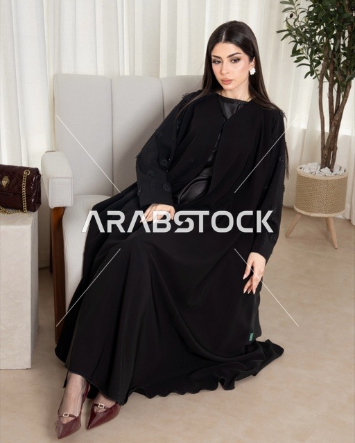 امرأة سعودية بعباية سوداء عصرية تجلس على كرسي
