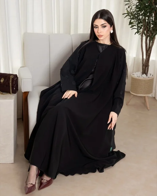 امرأة سعودية بعباية سوداء عصرية تجلس على كرسي