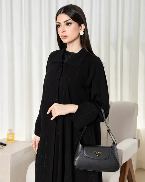 امرأة سعودية بعباءة سوداء عصرية وحقيبة يد